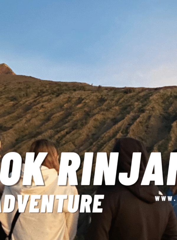 Group of hikers looking up at the steep, scree-covered slope of the Rinjani summit at sunrise, ready for the final ascent.