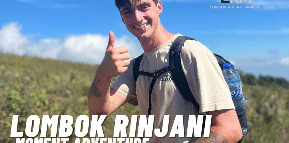 A smiling male hiker with a backpack gives a thumbs-up gesture on a sunny, grassy slope of Mount Rinjani.